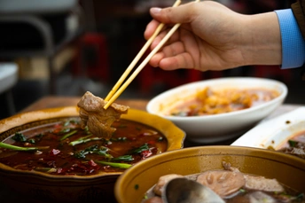 一个人正在碗里盛汤时 另一个人正在盘子里盛食物 手里拿着勺子。