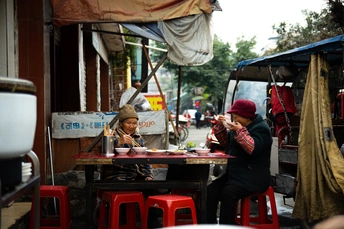 一个妇女和一个孩子在一个繁忙的街道上的户外餐厅吃食物。