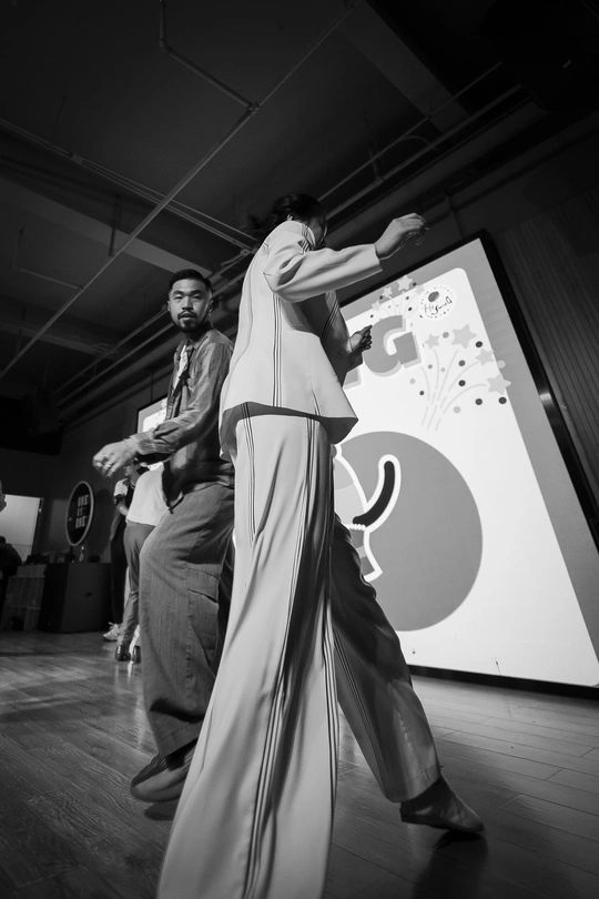 一张黑白照片 描绘了一对男女在舞台上跳舞 而其他人站在背景中。