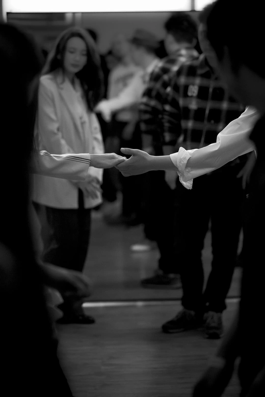 一张黑白照片 一个人手握遥控器 其他人在背景中站立。