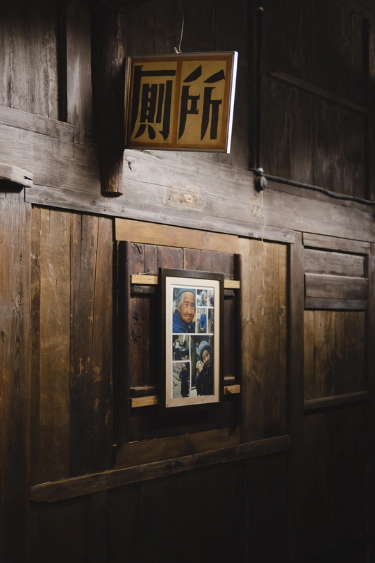 一座有木墙和门 上面挂着海报和标志的老房子