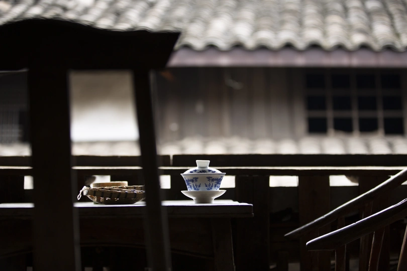 一个蓝色的花瓶放在一个木制桌子上 桌子上还放着一把椅子 在一个小房间里。