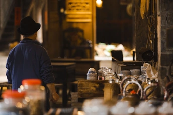 一个戴帽子的人在厨房里看着桌子上的食物