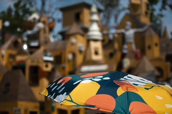 一个人手持彩色雨伞 背景中有微缩建筑。