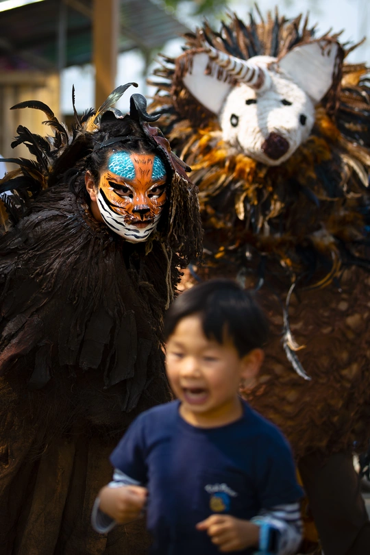一个脸上画了图案的男孩走过一个穿着服装的男人