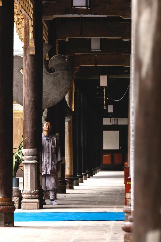 一位男士走在一座大石柱和支柱的寺庙走廊里