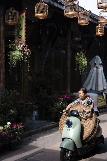 一位女士骑着小摩托车沿着街道行驶