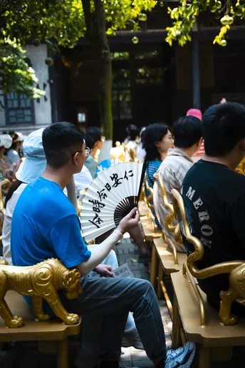 一个坐在长凳上的人带着雨伞 还有其他人坐在桌子旁。