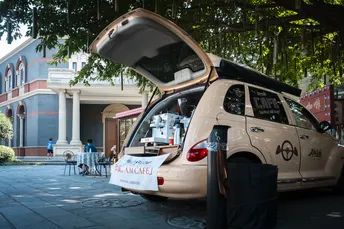 一辆带有敞篷车尾的小汽车停在建筑物前面的一条街道上。