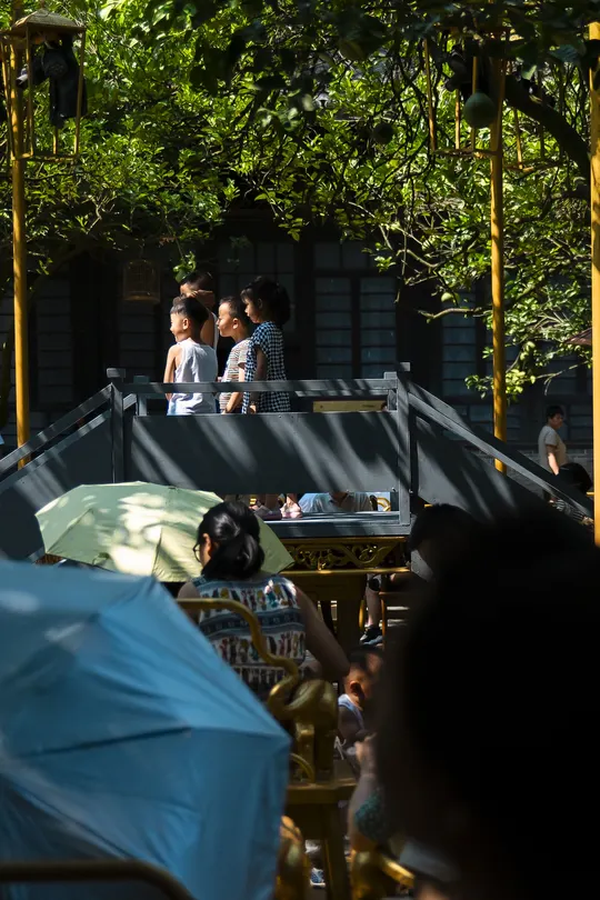 人们坐在户外桌子旁 带着伞