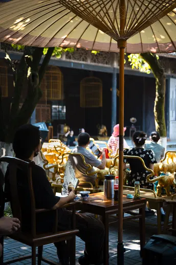 一个男子和一个女子坐在夜晚的露天餐厅里 桌子上有遮阳伞。