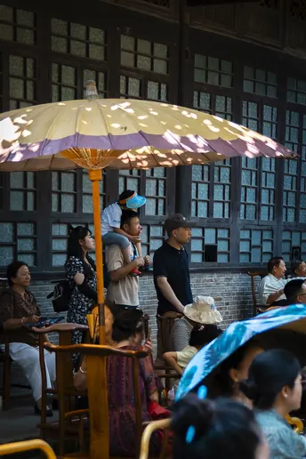 一群人在一间房间的下面的大型遮阳伞下坐着