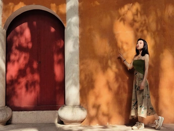 站在橙色墙壁和红色门前的年轻女子