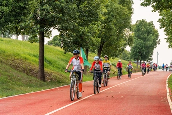 人们在公园的小路上骑自行车 而另一个骑自行车的人在路上骑行