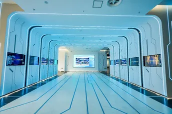 一个长长的隧道 地板和墙壁都是蓝色的 天花板也是蓝色的 并且有灯光。