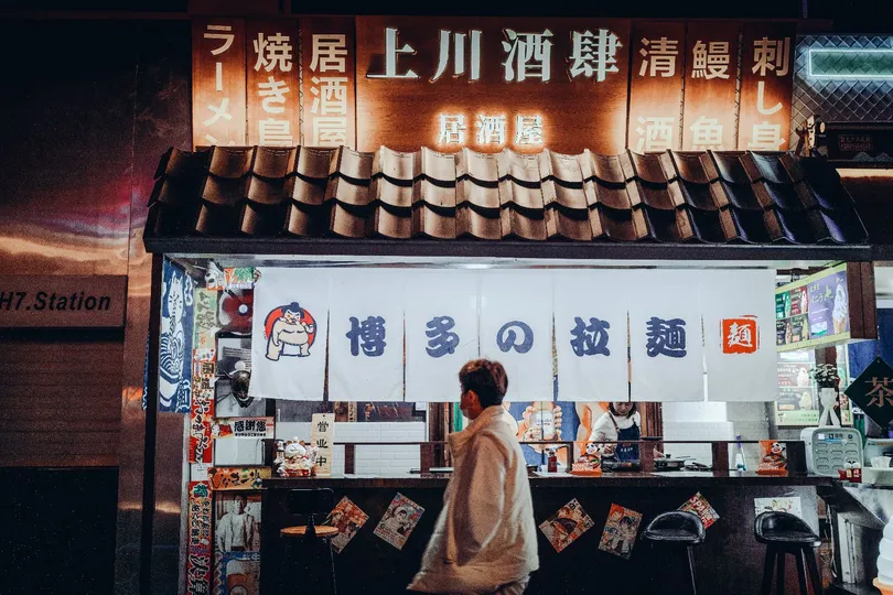 一位站在夜晚小餐馆前 women standing in front of a small rest