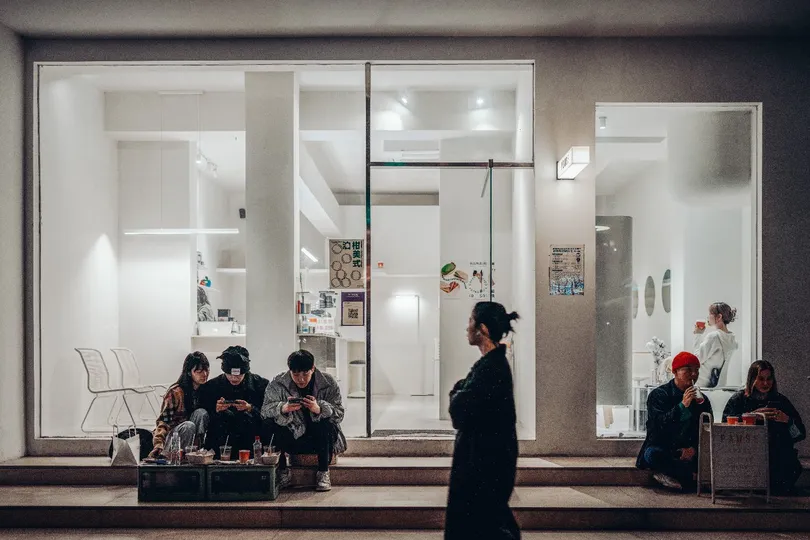 夜晚时分 一个人站在窗户前 周围有几个人坐着。