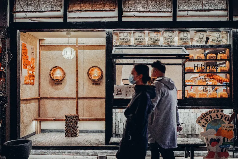 一个男人和一个女人站在商店前面 晚上看着餐厅的窗户。