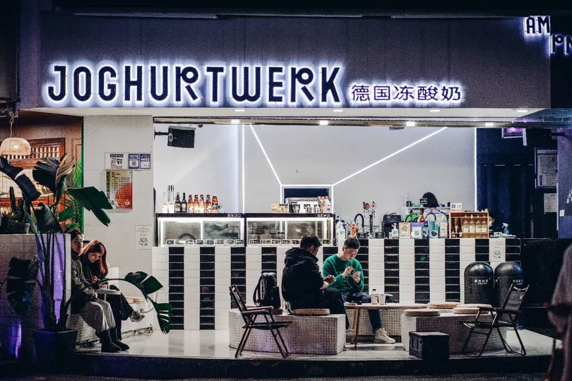 人们在夜晚坐在餐厅外面的桌子旁