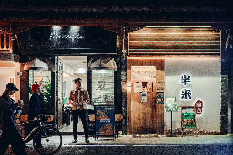 一个夜晚 一个男子走在街上 推着他的自行车经过一家商店。