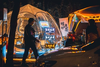 一个夜晚在街上行走的人 帐篷都亮着灯。