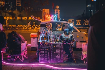 一个街头小贩在晚上出售饮料 人们站在街边。