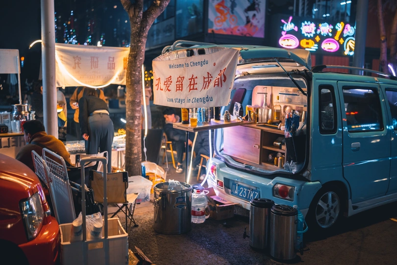 夜幕下 一辆蓝色的汽车停在美食卡车旁边