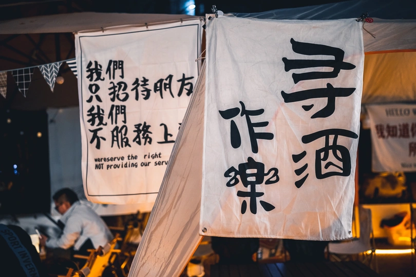 一个男人在挂一面带有亚洲文字的白色旗帜