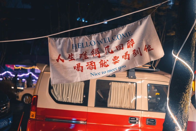 一辆红色和白色的公交车停在夜晚的街道上 上面有灯光和带有亚洲文字的标志。