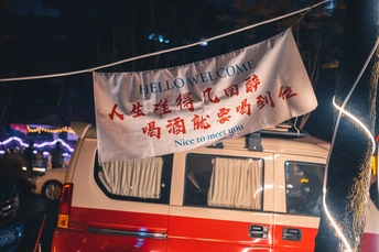 一辆红色和白色的公交车停在夜晚的街道上 上面有灯光和带有亚洲文字的标志。