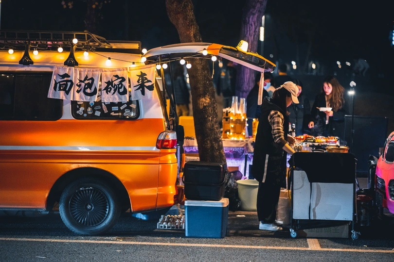 夜晚路边停着一辆小货车旁站着一些人