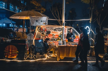 晚上街上的人们带着食物卡车和遮阳伞走动。