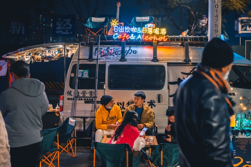 人们在食物卡车前的一张桌子旁坐着。