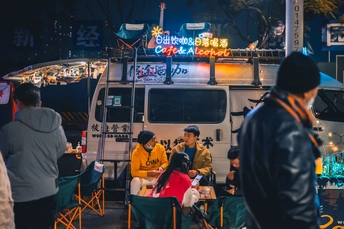 人们在食物卡车前的一张桌子旁坐着。