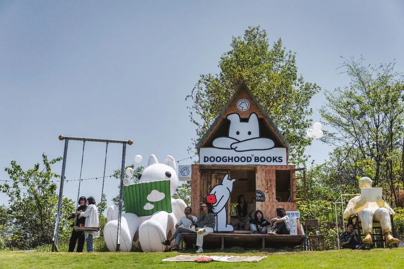 站在一个用假动物建成的小屋附近的田野上的人们