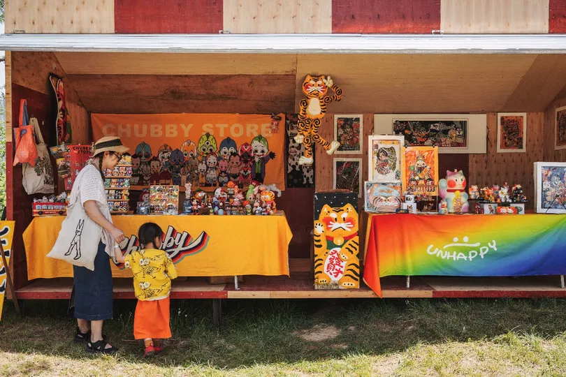 一个男子和一个孩子正在看一个卖玩具的摊位。