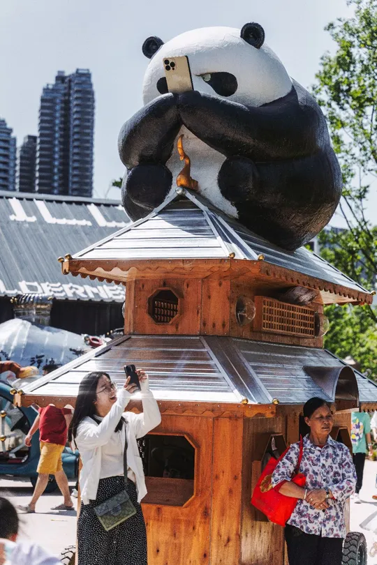 人们在节日上围着一只大熊猫拍照