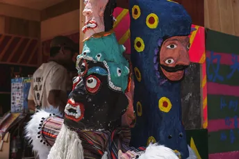 一个人站在一个有面具的木材柱子旁边