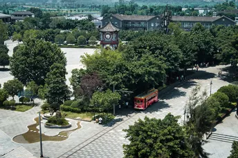 一个大公园 有树和一辆红色的公交车在街上。
