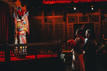 一个男人和一个女人站在夜晚的舞台上 前面有一栋建筑。