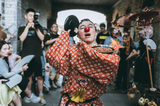 一个人穿着传统小丑服装站在人群前面。