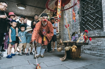 一个穿小丑服装的人在街上娱乐孩子