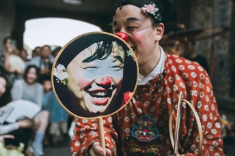 一个化身为小丑的男人举着镜子照着自己的脸