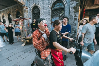 一位中国街头骑着滑板车的女士与一群游客在一起。