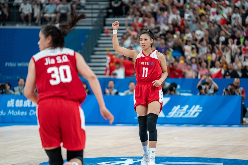 一名篮球运动员在比赛中为她的队伍在场上与观众一起欢呼。