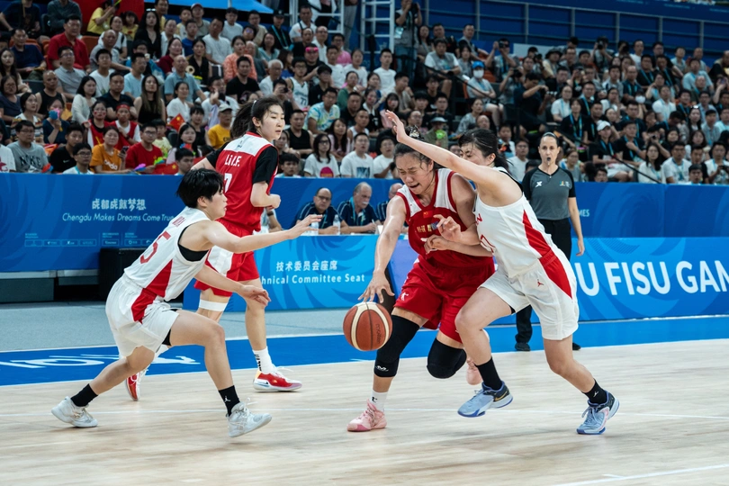 一群男人在一个有很多人在观看的篮球场上打篮球。