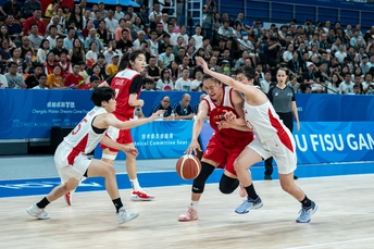 一群男人在一个有很多人在观看的篮球场上打篮球。