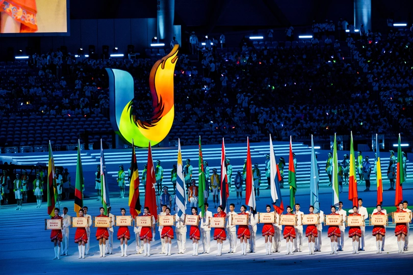 开幕式上 表演者手持不同颜色的旗帜排列成行。