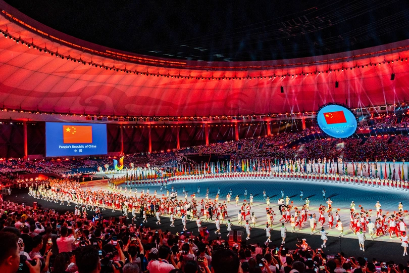 表演者在开幕式上在体育场舞台上表演 周围有大量人群。