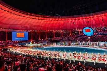 表演者在开幕式上在体育场舞台上表演 周围有大量人群。